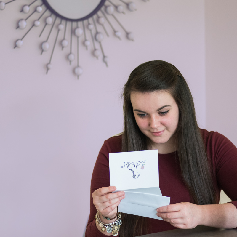 A woman reading a thoughtful card from a personalized pet sympathy gift sent to her after the loss of her beloved pet